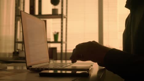 persona que trabaja en una computadora portátil y un teléfono inteligente en la oficina