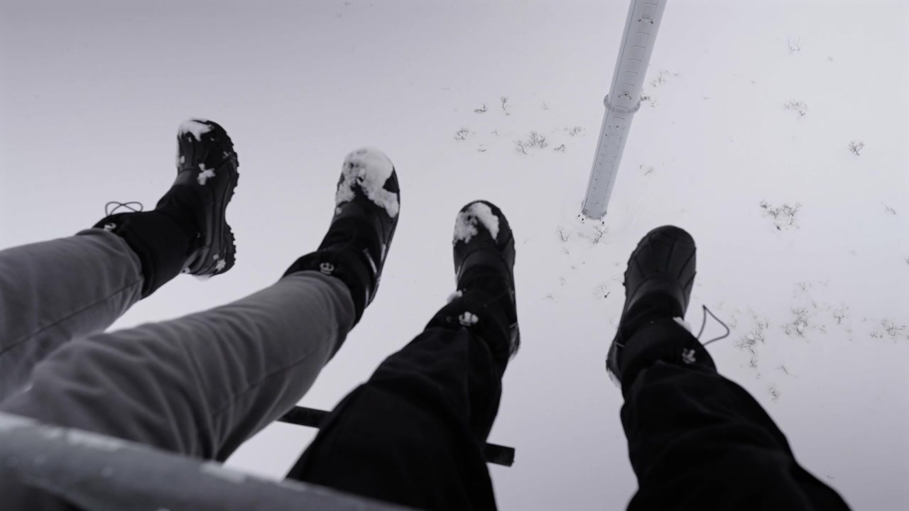 First person view on a ski lift above fresh snowy ground in Mendoza, Argentina, showcasing boots with snow, wintry light, elevated perspective, and immersive adventure atmosphere.