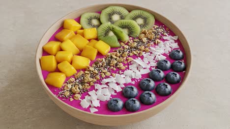 a vibrant and healthy smoothie bowl, featuring fresh mango, kiwi, blueberries, granola, coconut, and a bright dragon fruit base for an energizing breakfast