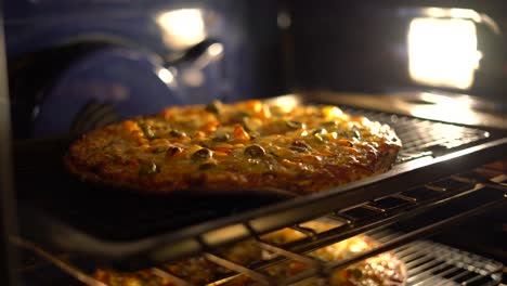 pizza bubbling in oven - homemade pizza cooking baking in hot stove with cheese bubbling. cooking italian pizza in electric convection oven. closeup of pizza topped with olives, cheddar and mozzarella