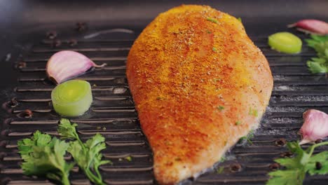 Cooking raw chicken meat in yellow turmeric spice with garlic and greens on grill close-up. Preparing raw food for cooking. Grilled chicken, duck, turkey kebab with vegetables.