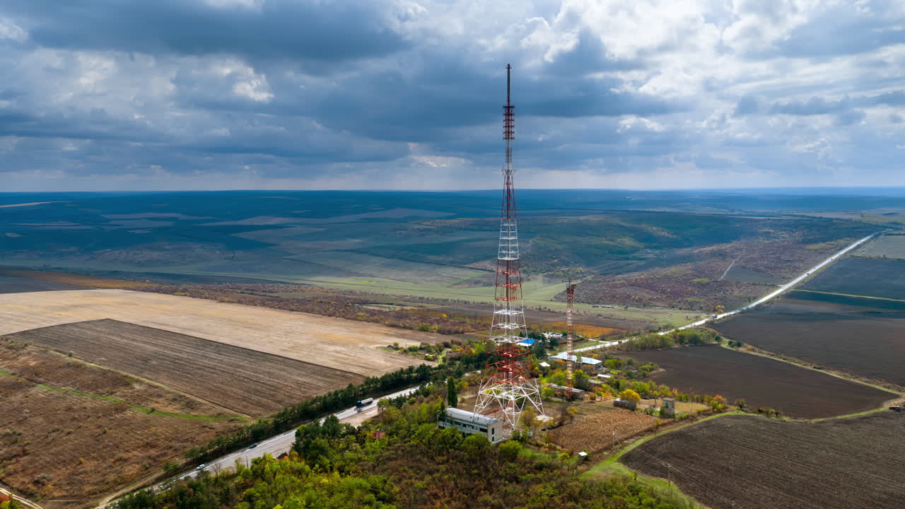 Aerial drone view of an electricity tower in the middle of a filed, near a road in Moldova time lapse