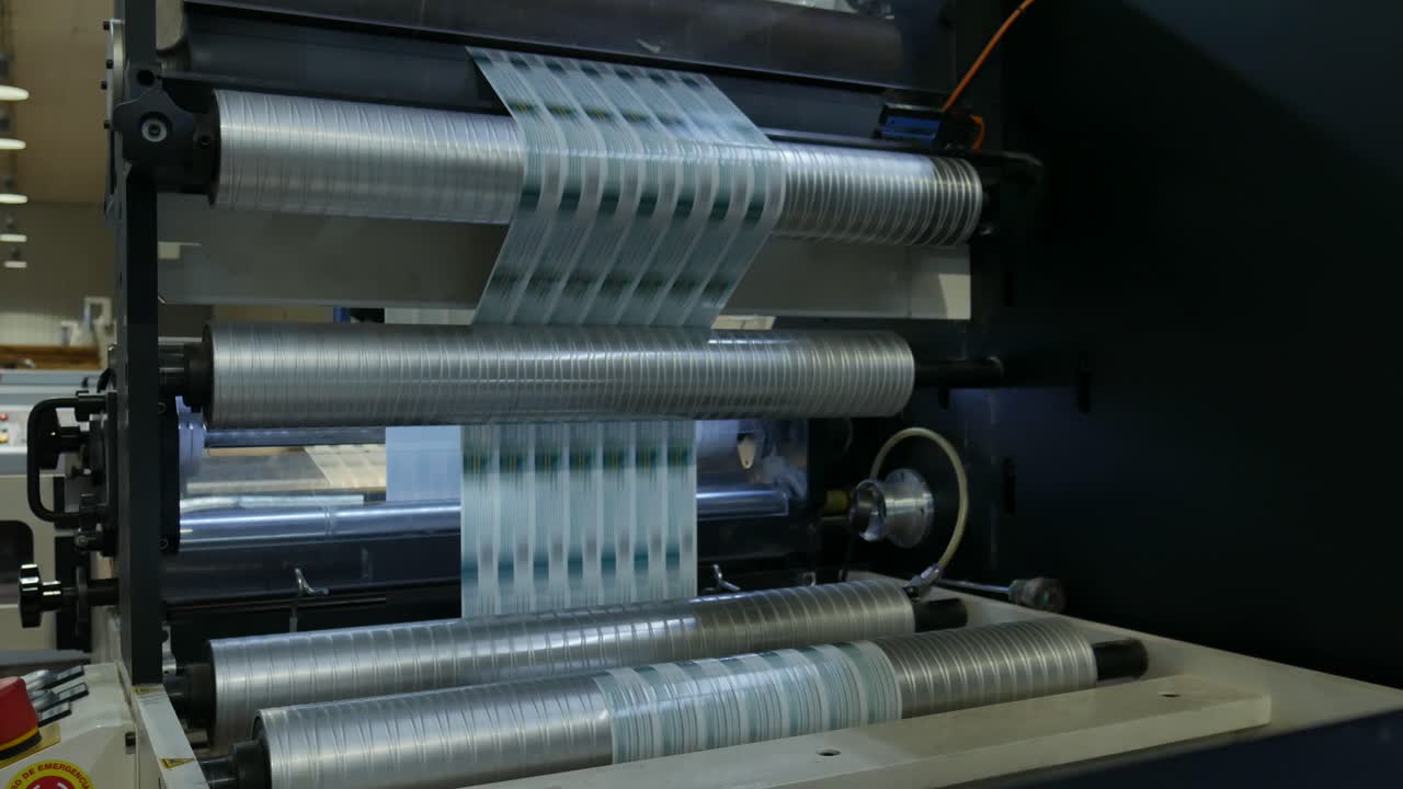 label machine working fast, rolls and ink do their job, red product labels are made in a chain in a labeling factory