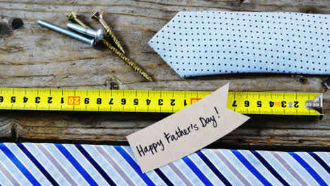 happy fathers day card, tie, screw, measuring tape on wooden plank