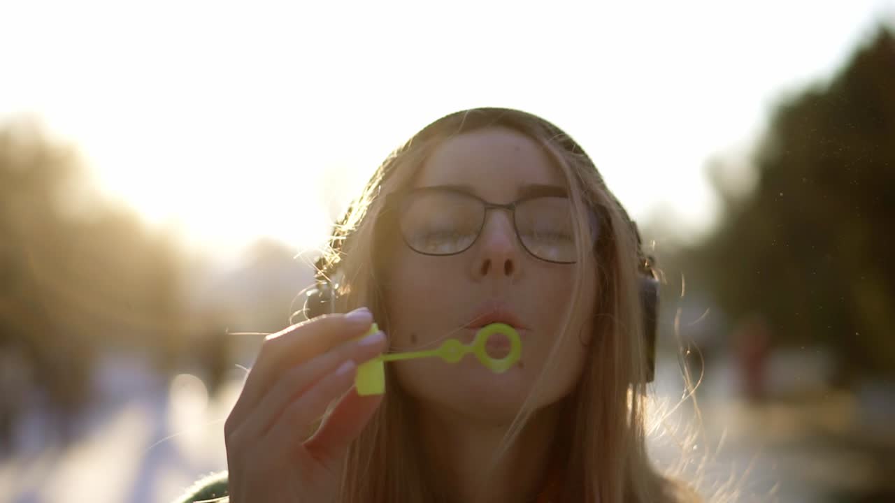 retrato de una mujer infla burbujas de jabón en invierno durante el clima frío, llamaradas de sol