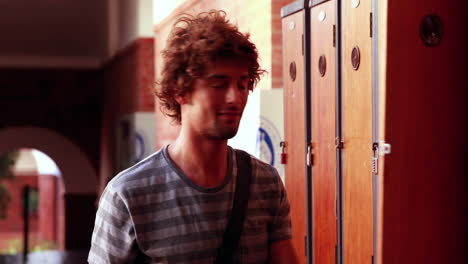 estudiante caminando hacia y abriendo su casillero