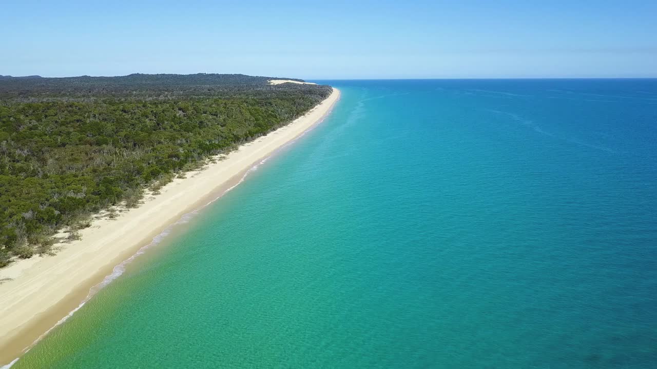 Drone footage of long white sandy beach on a calm sunny day at the Sandy Cape, Fraser Island, Queensland, Australia