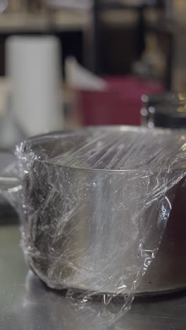 a person wrapping a bowl with plastic wrap
