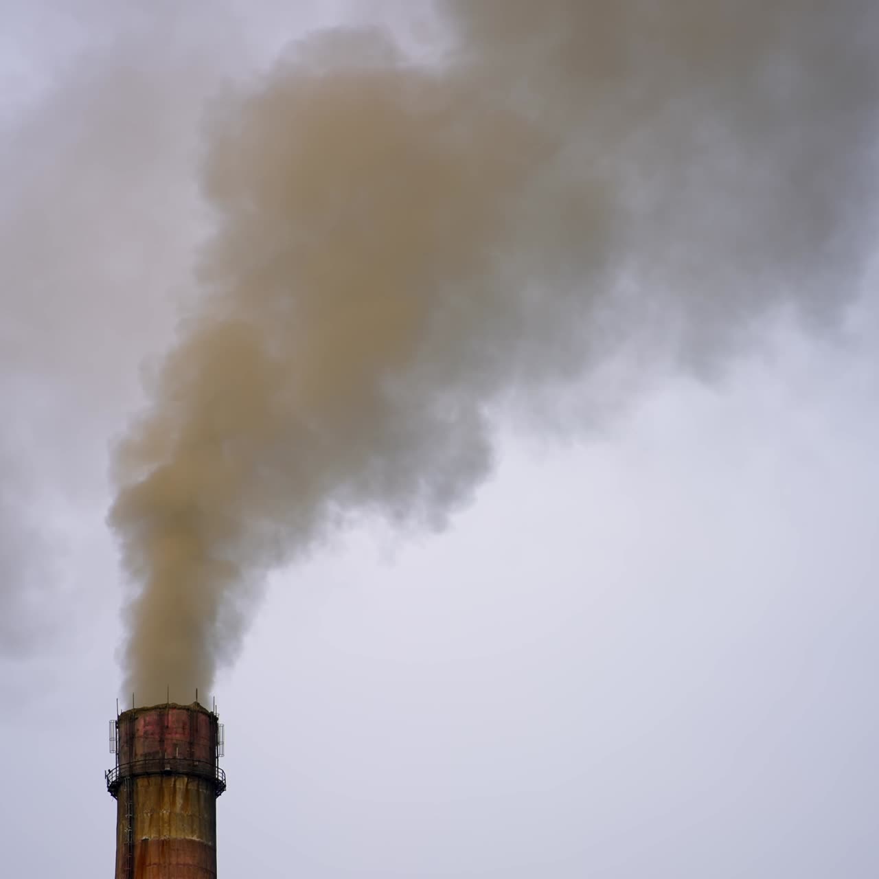 Smoking chimney against the grey sky. Air pollution. Thick smoke goes from industrial pipe. Ecological disaster. Harmful emissions fill the air in the evening