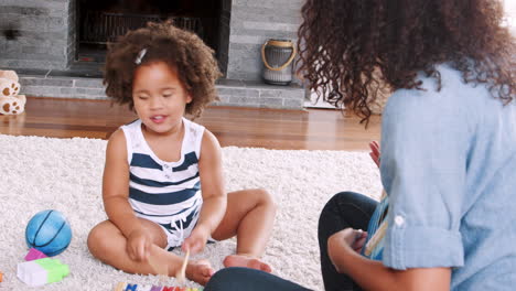 young black girl making a face and playing xylophone with mum