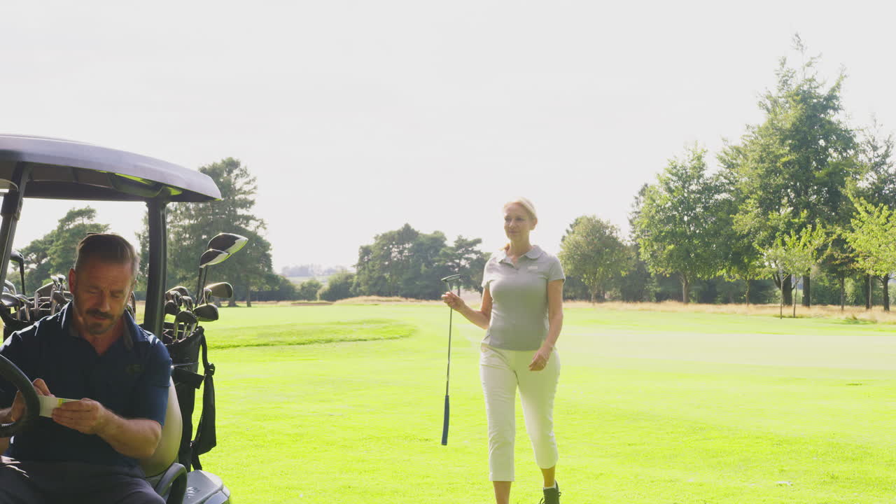 성숙 한 부부 가 함께 골프 를 치며 스코어 카드 와 함께 바기 에 앉아 있다