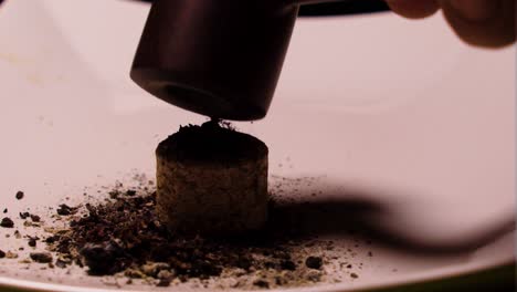 close up of a cork placed on a white plate to be used as a pipe knocker to clean up the remaining ash inside the smoking device antique vintage style used in modern days extreme close up indoor