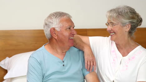 Pareja-Mayor-Sentada-En-La-Cama-Charlando