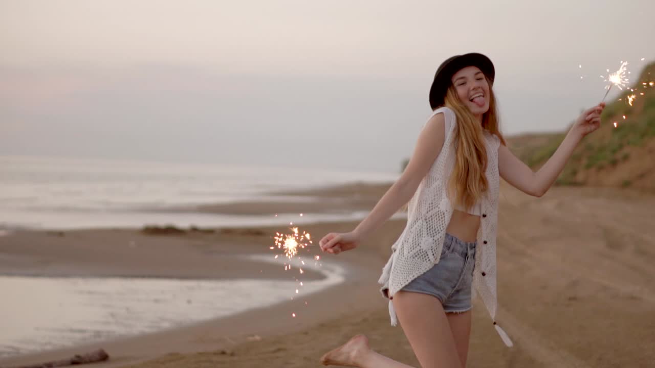 счастливая женщина с искрой на пляже на закате