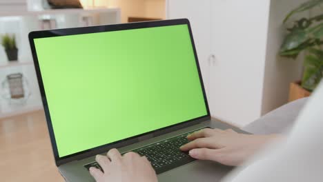 handle shot of woman using laptop with looking at green screen.