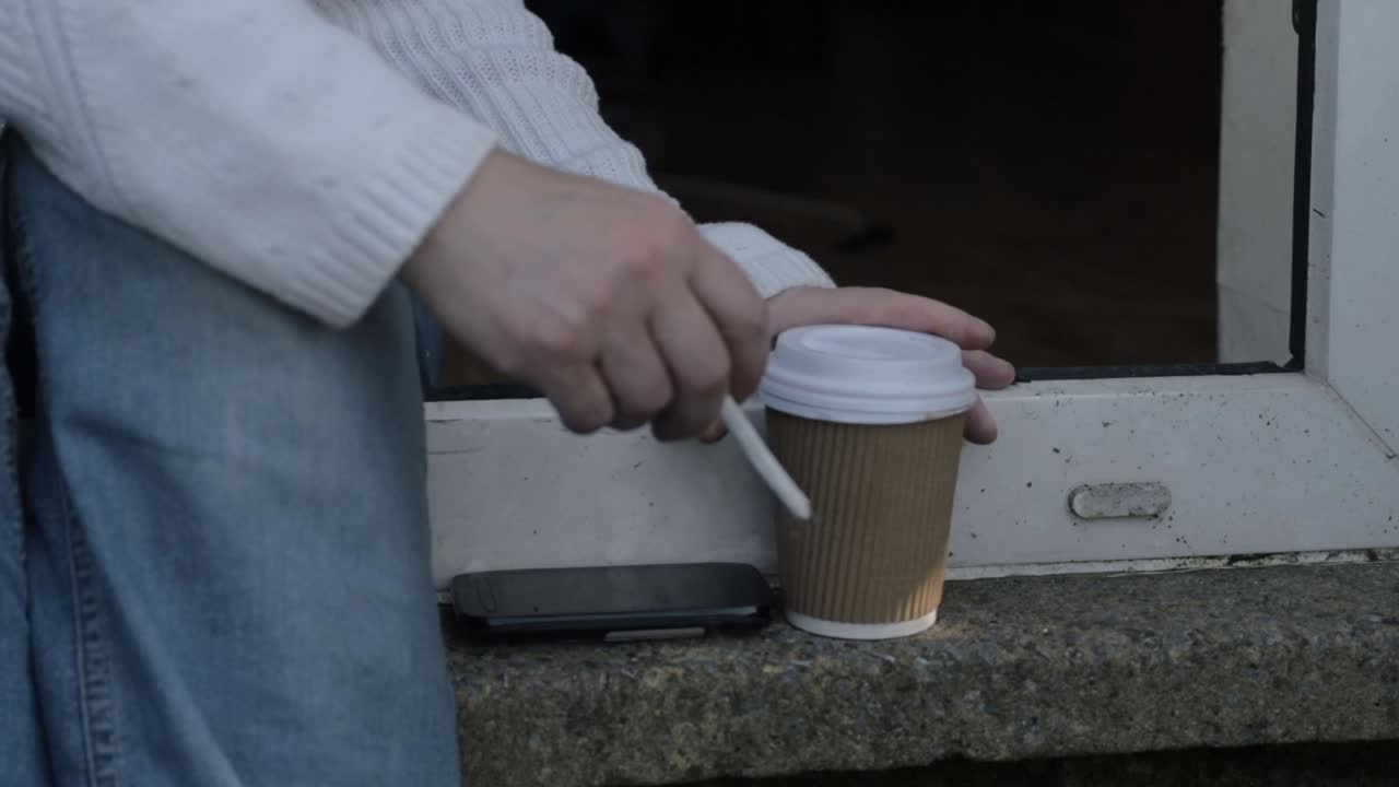Woman sitting on step smoking cigarette and drinking coffee medium shot