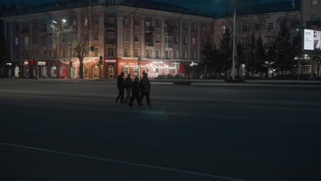 a night city scene featuring illuminated buildings and storefronts with decorative lights pole are crossing the street while cars drive by