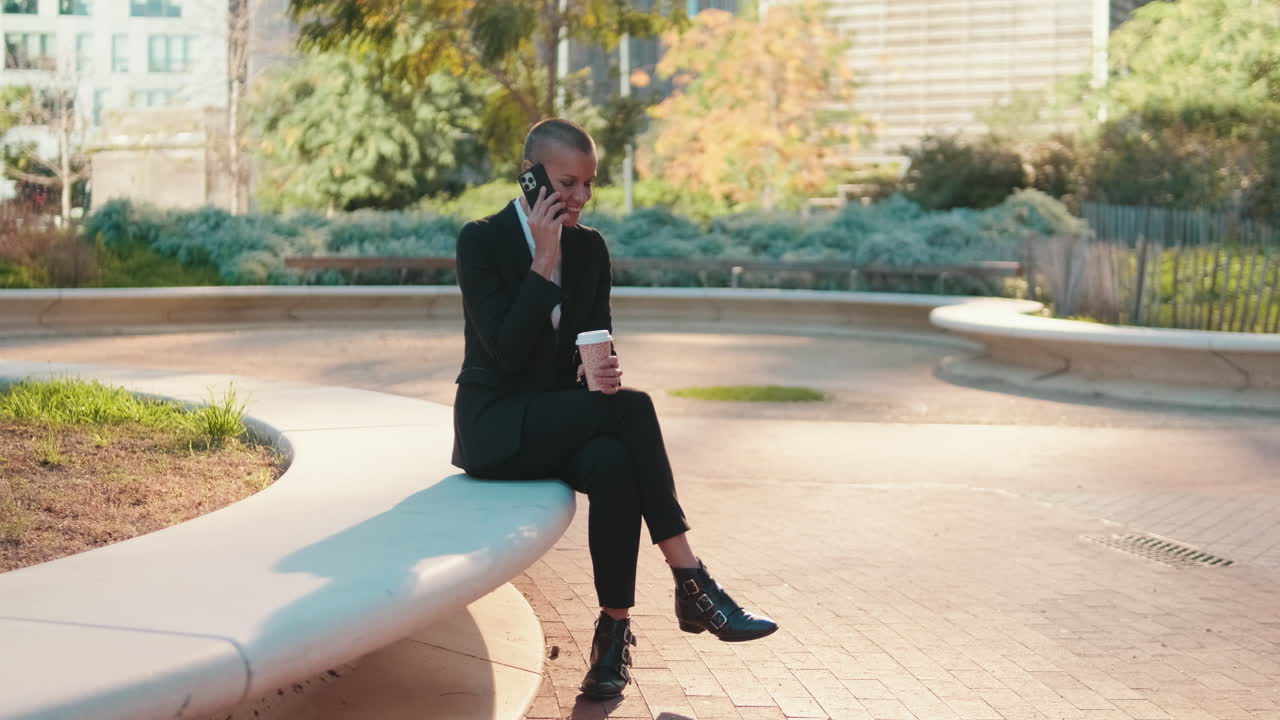 Donna sicura di sé che parla al telefono e beve caffè in un parco urbano