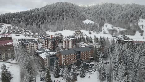 A-charming-ski-resort-village-nestled-among-snowy-trees-and-mountains,-offering-a-cozy-winter-escape