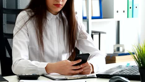 mujer de negocios usando un teléfono inteligente y sonriendo en una oficina moderna