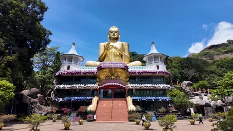 dambulla golden temple with its giant gold buddha statue in sri lanka, captured during a clear, sunny day. tilt up shot