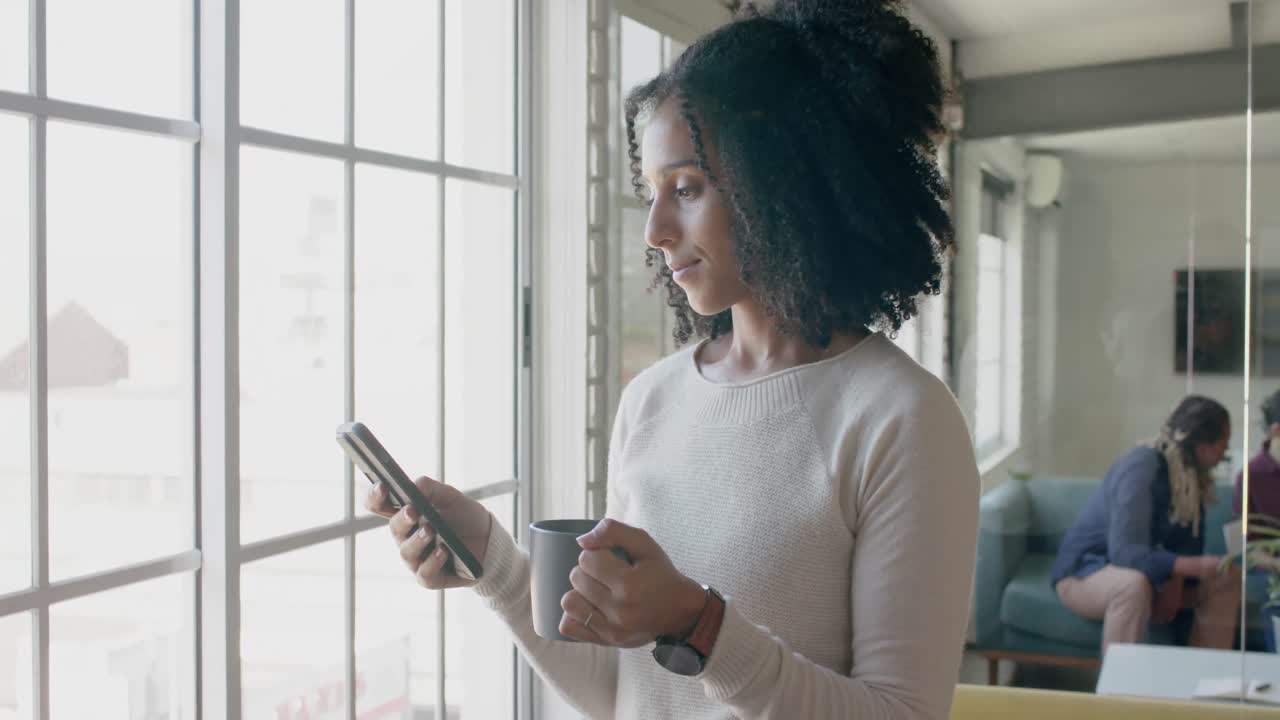Donna d'affari birazziale casual impegnata che usa lo smartphone in un ufficio creativo, slow motion