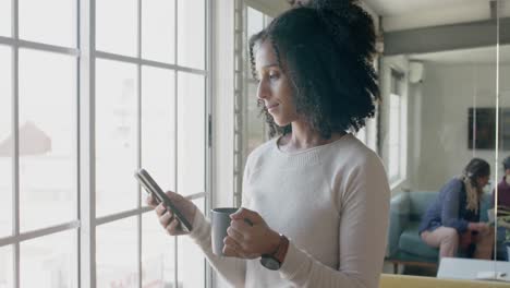 Busy-biracial-casual-businesswoman-using-smartphone-in-creative-office,-slow-motion