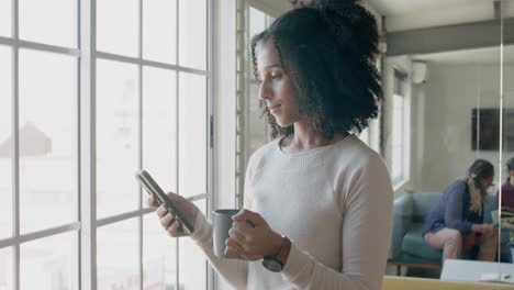 ocupada mujer de negocios casual biracial usando un teléfono inteligente en la oficina creativa, cámara lenta