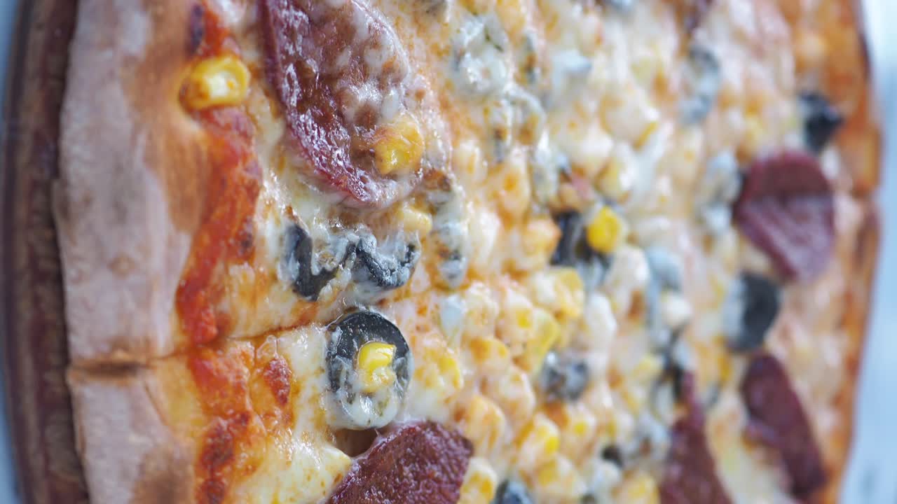 Pizza with corn, olives, sausage and cheese toppings