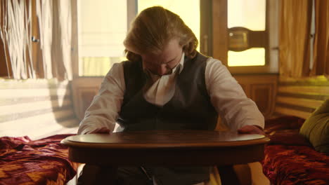 man looking intently at a table in a vintage room