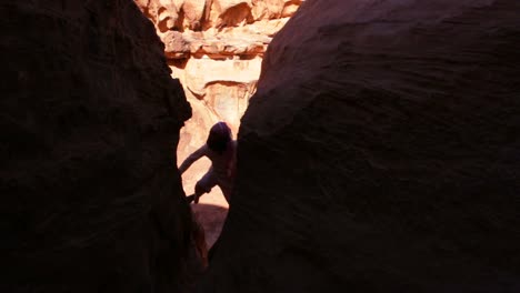 a bedouin man climbs up on cliffs in wadi rum jordan