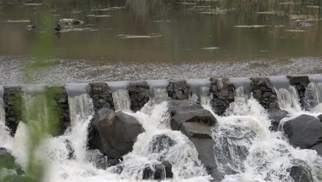 Rocky-Weir-Dam-Wall-Slows-Rushing-River-Water,-SLOW-MOTION