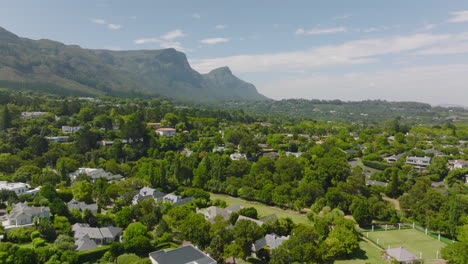 Forwards-fly-above-residential-suburb.-Luxurious-family-houses-arranged-between-lush-green-trees.-Cape-Town,-South-Africa