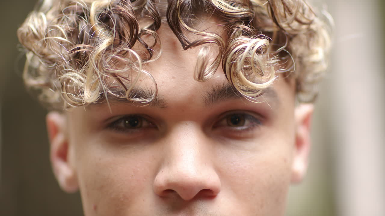 Close-up of young man with curly hair gazing intently, capturing emotion