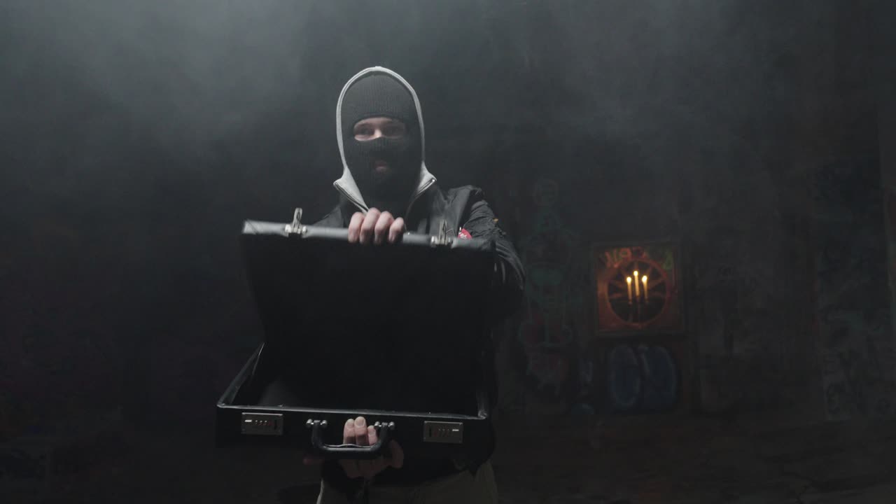 A masked man opens an empty briefcase in a dark smoky room, cinematic crime scene in slow motion