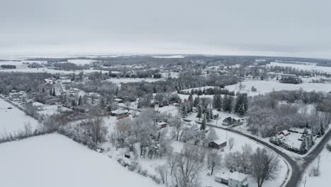 Houses-in-rural-community-and-landscape-covered-in-fresh-white-blanket-of-snow-in-winter