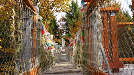 himalayan sidewalk, deep in nature skywalk wooden construction of viewpoint hitting by strong wind tree trunks colored flags during sunny autumn day captured in radhost, pustevny area 4k 60fps