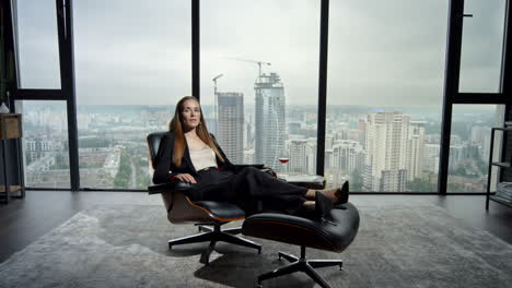 businesswoman relaxing on chair in modern interior. serious manager looking away