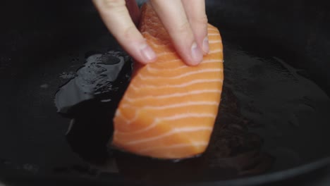 el chef coloca una rodaja de salmón en una sartén caliente