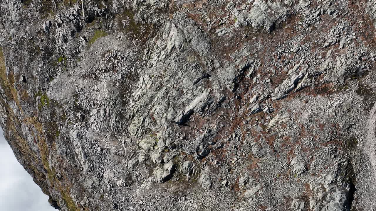 Drone ascends and rotates above a man standing on a cliff, revealing Cloudy Naeroyfjord and surrounding landscapes below