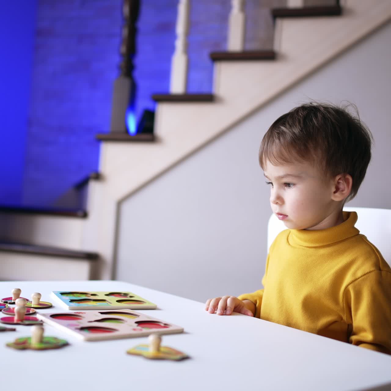 Bambino calmo e concentrato guarda i pezzi del puzzle. Il simpatico bambino si distrae dal puzzle e guarda di lato.