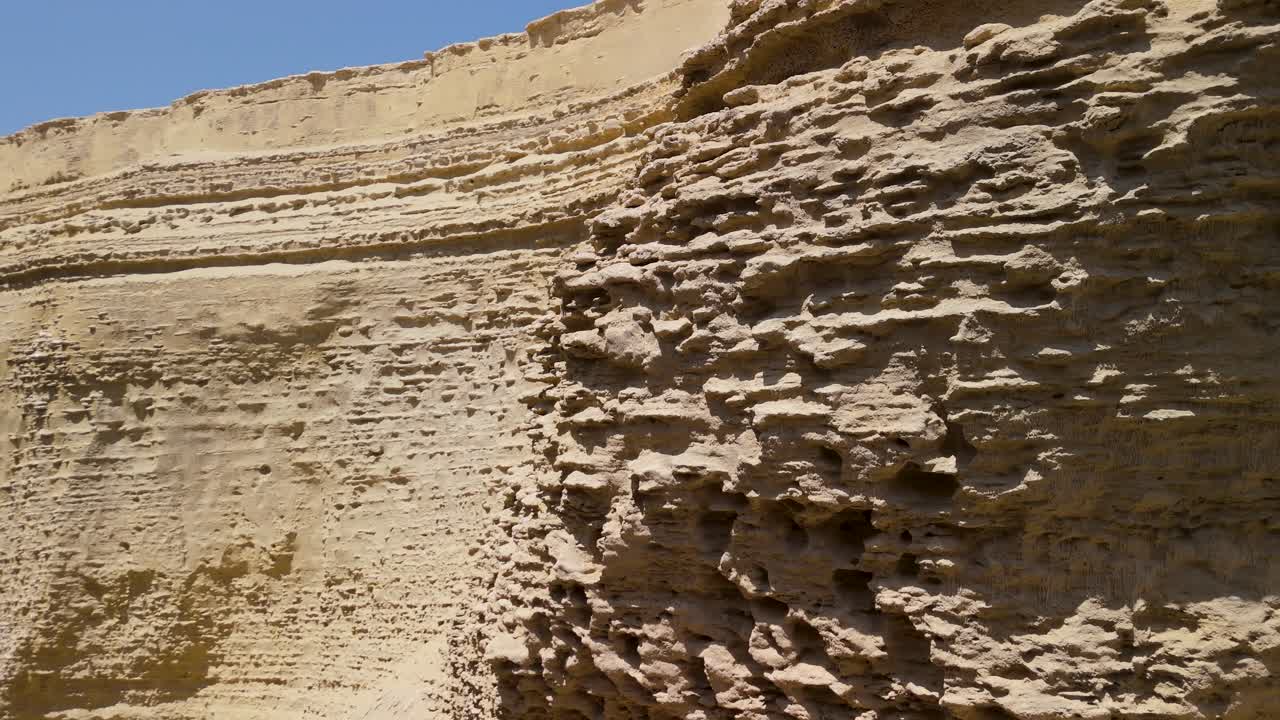 Aerial close-up pan shot showcasing the intricate eroded texture and geological layers of the sandstone walls in Cañon de los Perdidos Peru