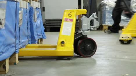 los trabajadores dentro de un almacén retiran manualmente la carretilla elevadora de la paleta de madera en el almacén centro industrial logístico de envío