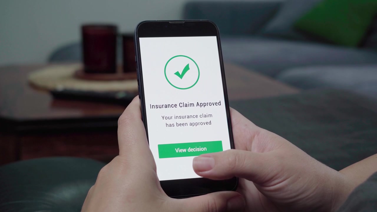 Primo piano di un'app mobile per assicurazioni che mostra una conferma di "Richiesta di risarcimento approvata" con un segno di spunta verde e un pulsante "Visualizza decisione".