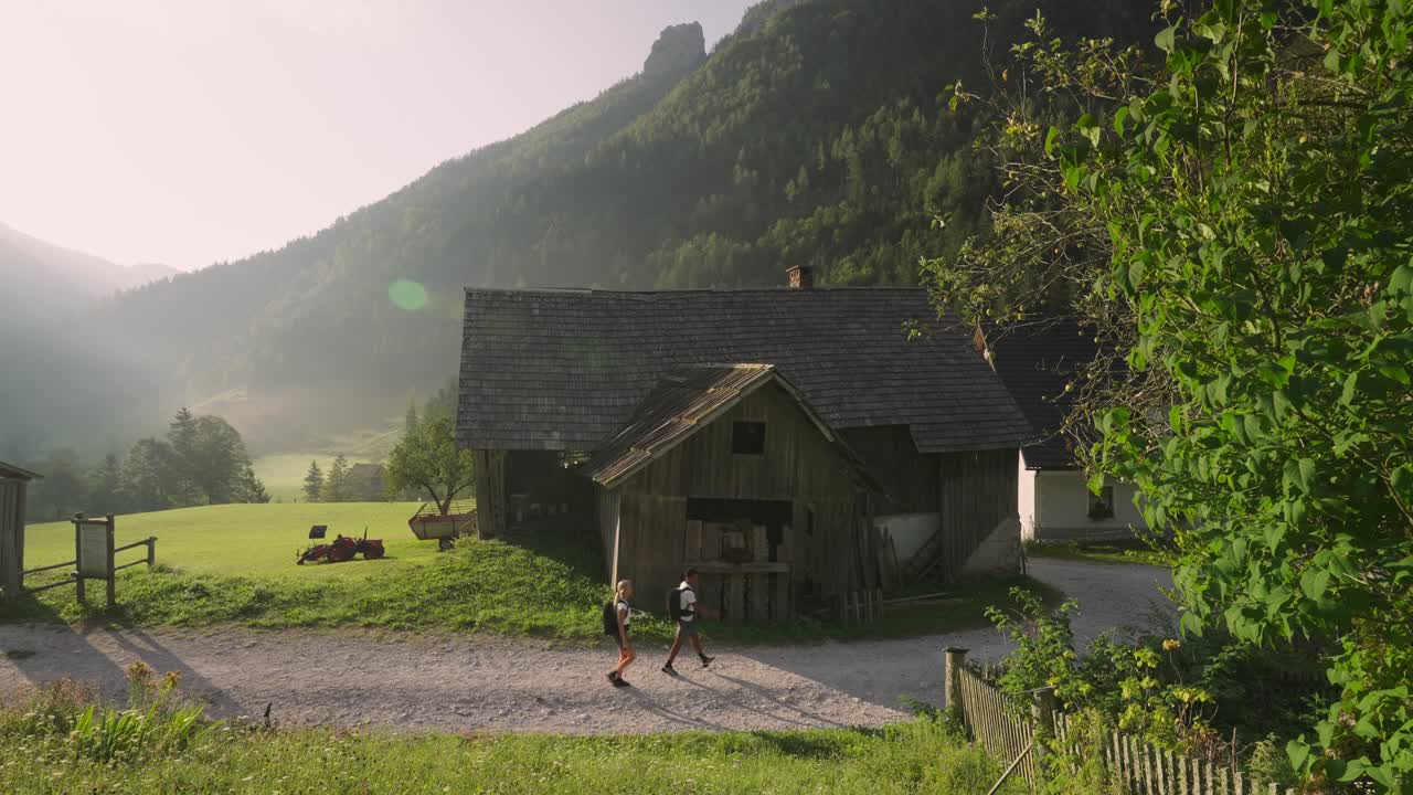 una pareja de caminatas cerca de una granja rústica en el valle de robanov planina, eslovenia al amanecer