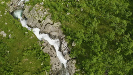 Aufschlussreiche-Aufnahme-Des-Bemerkenswerten-Hydalen-Tals-In-Norwegen-In-Der-Nähe-Des-Schmalen-Baches-Und-Der-Landschaft-Voller-Grüner-Bäume-–-Nach-Oben-Geneigte-Drohne