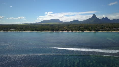drone-shot-panning-right-above-the-indian-ocean-and-revealing-the-coast-of-Mauritius-island-and-the-mountains-in-the-background