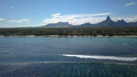 Drohnenaufnahme,-Die-Direkt-über-Dem-Indischen-Ozean-Schwenkt-Und-Die-Küste-Der-Insel-Mauritius-Und-Die-Berge-Im-Hintergrund-Sichtbar-Macht