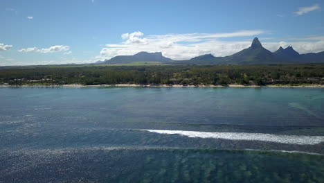 disparo de drones panorámico justo sobre el océano índico y revelando la costa de la isla de mauricio y las montañas en el fondo
