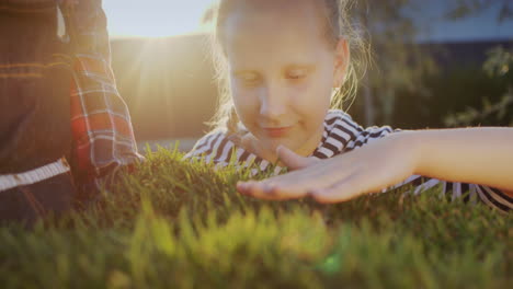 girl strokes the sprouts of green grass, a piece of land with grass is held in the hands of a farmer.